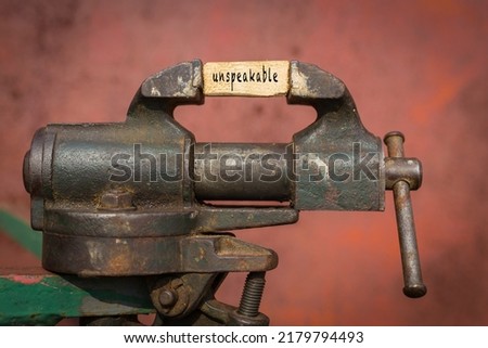 Concept of dealing with problem. Vice grip tool squeezing a plank with the word unspeakable