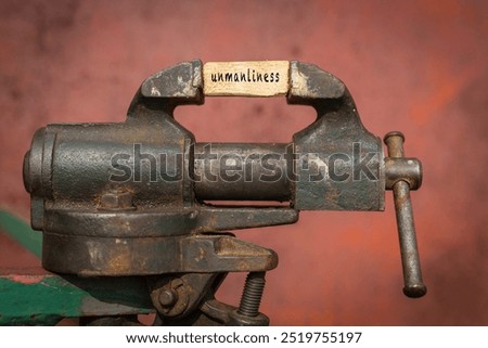 Concept of dealing with problem. Vice grip tool squeezing a plank with the word unmanliness