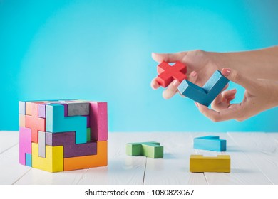 Concept of decision making process, logical thinking. Logical tasks. Conundrum, find the missing piece of the proposed. Hand holding wooden puzzle element. Hand sets the last element of the puzzle. 