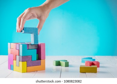 Concept of decision making process, logical thinking. Logical tasks. Conundrum, find the missing piece of the proposed. Hand holding wooden puzzle element. Hand sets the last element of the puzzle.  - Shutterstock ID 1080823082