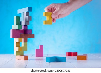 Concept of decision making process, logical thinking. Logical tasks. Conundrum, find the missing piece of the proposed. Hand holding wooden puzzle element.