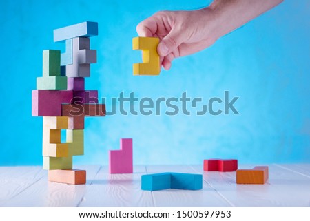 Concept of decision making process, logical thinking. Logical tasks. Conundrum, find the missing piece of the proposed. Hand holding wooden puzzle element.