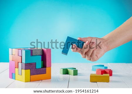 Concept of decision making process, logical thinking. Logical tasks. Conundrum, find the missing piece of the proposed. Hand holding wooden puzzle element. Hand sets the last element of the puzzle.	