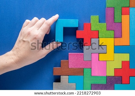 Concept of decision making process, logical thinking. Logical tasks. Hand holding wooden puzzle element. Hand sets the element of the puzzle.