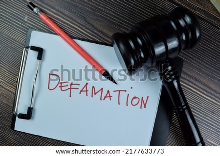 Concept of Defamation write on a paperwork isolated on Wooden Table.