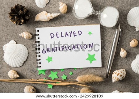Concept of delayed gratification. Text on paper decorated with seashells indoors studio shot.
