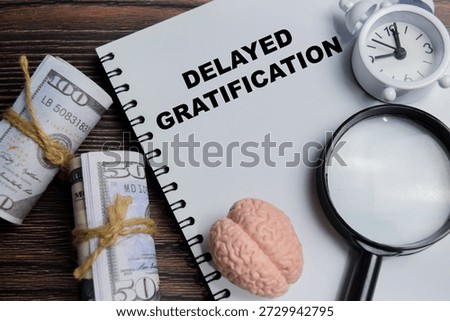 Concept of delayed gratification write on book isolated on Wooden Table. For mindset, self control and discipline patience for long term