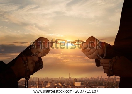 The concept of dependence in business between businessmen. Businessmen clothes each other in chains on the background of a sunny sunset.