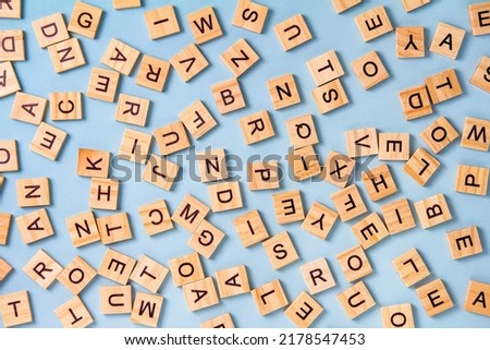 The concept of developing thinking, grammar, back to school, learning. Top view of square wooden tiles with the English alphabet lying on a blue background.