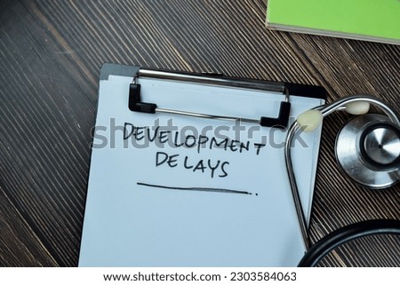 Concept of Development Delays write on paperwork with stethoscope isolated on Wooden Table.