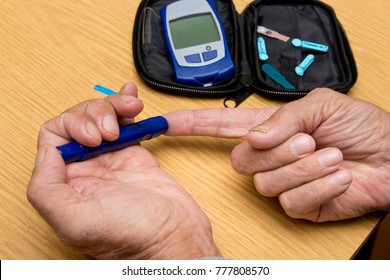 Concept Diabetes In The Elderly Retired. Senior Man With Glucometer Checking Blood Sugar Level At Home. Learn To Use A Glucometer