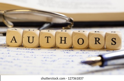 Concept Of Dices With Letters Forming Words: Authors. Generic Handwritten Text, Pen, Glasses And Books As Background.  Dices Made From Wood With Natural Imperfections.