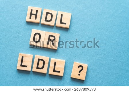 Concept of difference between HDL and LDL cholesterol, with terms composed with wooden alphabet on a blue background; bad cholesterol LDL.
