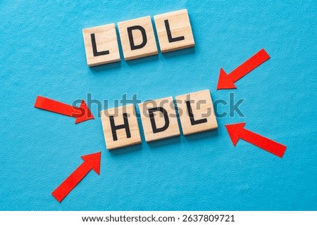 Concept of difference between HDL and LDL cholesterol, with terms composed with wooden alphabet on a blue background, good cholesterol HDL.
