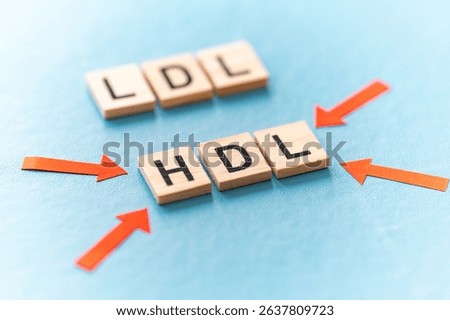 Concept of difference between HDL and LDL cholesterol, with terms composed with wooden alphabet on a blue background, good cholesterol HDL.
