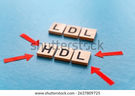 Concept of difference between HDL and LDL cholesterol, with terms composed with wooden alphabet on a blue background, good cholesterol HDL.
