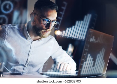 Concept of digital diagram,graph interfaces,virtual screen,connections icon.Young entrepreneur working at modern office on laptop.Man using digital touch pad at night,blurred background.Horizontal
