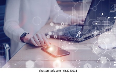 Concept of digital screen,virtual connection icon,diagram,graph interfaces.Pensive young beautiful businesswoman using modern mobile phone and laptop while sitting at her working place.Flares