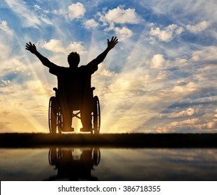 Concept of disability and disease. Silhouette happy disabled person in a wheelchair at sunset and reflection in water - Shutterstock ID 386718355