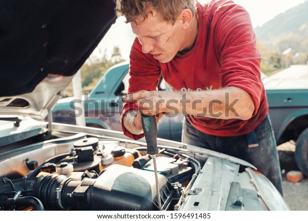 The
concept of disability of people and their adaptation to life. A
blond disabled man repairs a car, works with a screwdriver. There
are no fingers on his hands. Disabled from
childhood.