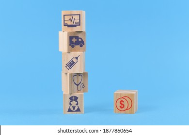 Concept For Discrepancy Between Costs For Medical Treatments And Funding Depicted With Wooden Blocks With Medical Icons Like Nurse And Ambulance And Dollar Sign