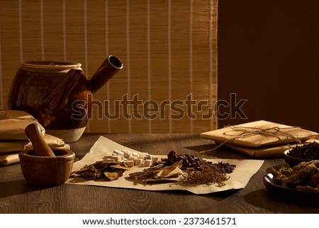 Concept of dividing herbs according to medicinal scale for daily intake. A medicinal kettle, and a sheet of paper containing various traditional medicines decorated on wooden table