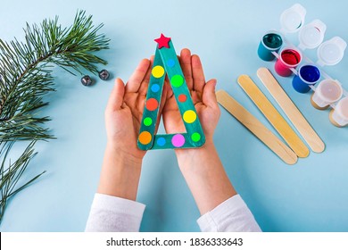 Concept of DIY and kid's creativity. Step by step instruction: how to make christmas tree made of ice cream sticks. Step 5 Child's holding  finished New year handmade craft tree. - Powered by Shutterstock