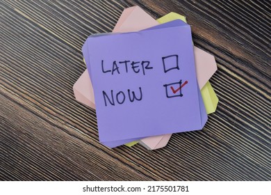 Concept of do it now or later write on sticky notes isolated on Wooden Table. Selective focus on later and now text