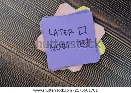 Concept of do it now or later write on sticky notes isolated on Wooden Table. Selective focus on later and now text