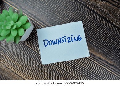 Concept of Downsizing write on sticky notes isolated on Wooden Table.