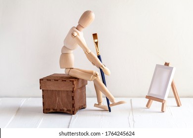 Concept for drawing. Wooden Mannequin For Painting With brush and malbert. Pensive artist sitting at a painting - Powered by Shutterstock