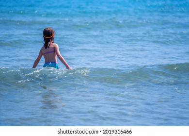 Concept: Drowning Dangers For Kids And Outdoor Water Safety For Parents. Beautiful Young Girl Swims Alone In The Sea. Copy Space. Horizontal Image.