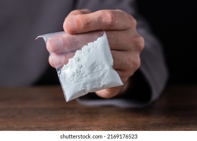 Concept drug addiction. Man hand holds plastic packet or bag with cocaine or another drugs, drug abuse and danger addiction concept.