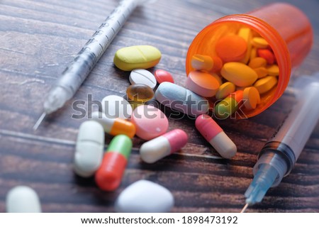 the concept of drug overdose, syringe and pills on dark background, close up 
