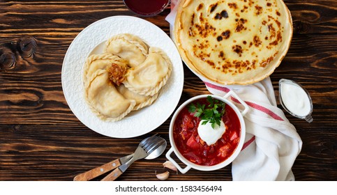 The Concept Of Eastern European National Cuisine. Ukrainian, Russian, Polish Food.Traditional Beetroot Soup Borscht With Sour Cream, Pancakes Blini, Dumplings Vareniki With Potatoes And Fried Onions