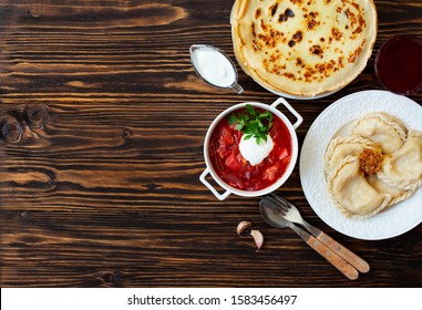 The Concept Of Eastern European National Cuisine. Ukrainian, Russian, Polish Food.Traditional Beetroot Soup Borscht With Sour Cream, Pancakes Blini, Dumplings Vareniki With Potatoes And Fried Onions