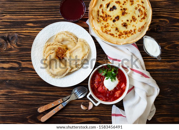 The concept of Eastern European national cuisine.\
Ukrainian, Russian, Polish food.Traditional beetroot soup Borscht\
with sour cream, pancakes Blini, dumplings Vareniki with potatoes\
and fried onions