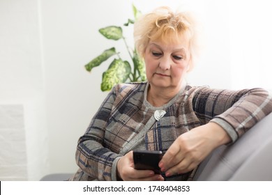 Concept of easy, fast usage of modern technology among all ages. Portrait of confident mature woman with wrinkles she is using her modern smartphone for sending a message isolated on gray background