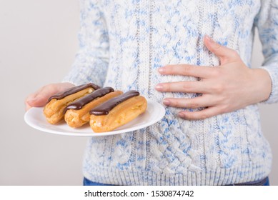 Concept Of Eating Too Much Sweet Food. Cropped Close-up Photo Of Woman Holding Plate With Delicious Glazed Cupcakes Holding Hand On Full Tummy Isolated Grey Background