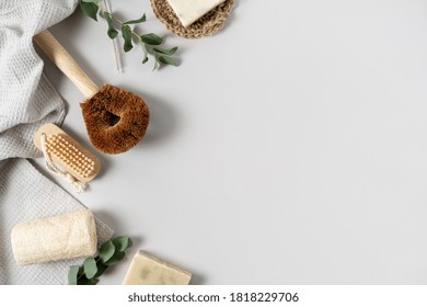 Concept Of Eco Friendly And Biodegradable Items. Flat Lay, Top View Of Kitchen And Bathroom Supplies, Coconut Brush, Loofah Sponge, Soap, Towel And Eucalyptus Plant On White Copy Space Background