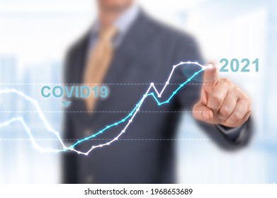concept of economic recovery in 2021 after the fall due to the covid 19 coronavirus pandemic. Businessman pointing graph corporate future growth plan 2021 on blurred office background