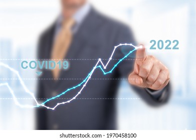 concept of economic recovery in 2022 after the fall due to the covid 19 coronavirus pandemic. Businessman pointing graph corporate future growth plan 2022 on blurred office background