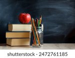 The concept of education, stack of books, an apple, pencils against the background of the school blackboard