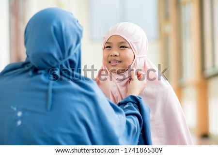 Concept Eid mubarak, Muslim girl, Islamic girl, teasing mother with love and mother watching beautiful hijab at mosque after prayer.