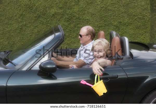 Concept of an elderly couple driving to the seaside\
with a bucket and spade