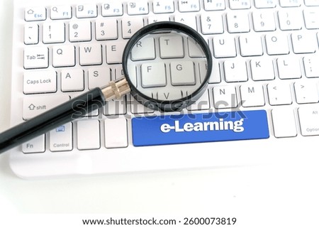 Concept e-Learning, Text "e-Learning" on Blue Key of White Keyboard under Magnifying glass; 