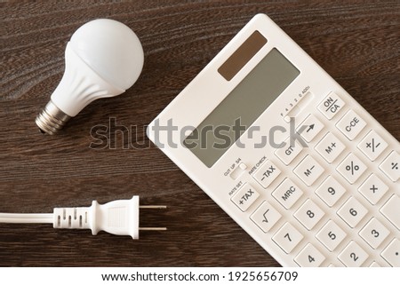Concept of electricity charge (light bulb, calculator and plug)