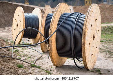 Concept of electricity supply for construction projects. Several wooden coils with power cable laid in trench.