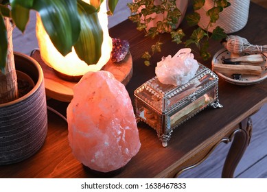 Concept Of Eliminating Negative Energy, Uplifting Your Spirit And Calming The Mind At Home. Salt Lamps, Crystal Quartz, Palo Santo Woods And White Sage At Wooden Desk At Dark Room. 