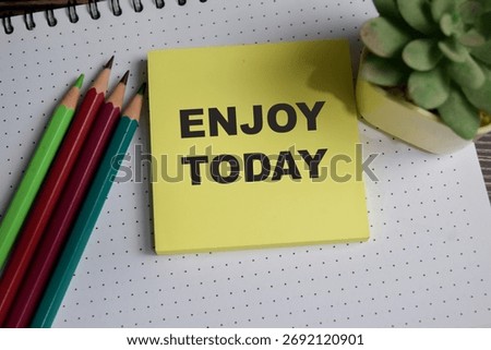 Concept of enjoy today write on sticky notes isolated on Wooden Table.